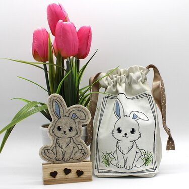 Bestickter Zugbeutel mit Osterhasenmotiv und kleine Filz-Hasendeko vor pinken Tulpen