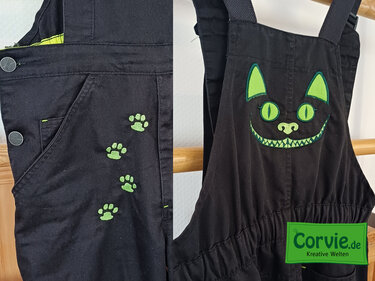 Schwarze Latzhose mit grüner Katzenkopf- und Pfotenstickerei