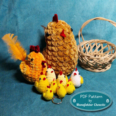 Mehrere gehäkelte gelbe und weiße Küken und Hühner in verschiedenen Größen neben einem Korb auf blauem Stoff