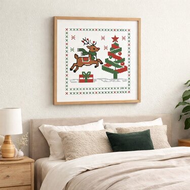 Framed cross-stitch Christmas design with a leaping reindeer, decorated tree and present in red and green above a bed.