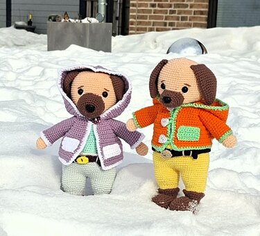 Zwei gehäkelte Amigurumi‑Hunde in Kapuzenjacken im Schnee