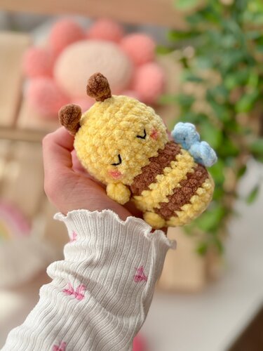 hand holding small yellow and brown crochet bumblebee amigurumi with blue wings