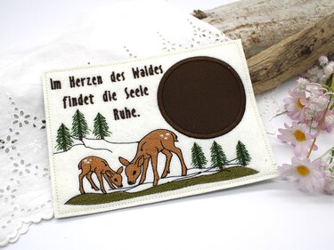Weißer bestickter Tassenteppich mit Rehmutter und Kitz im Schnee, Tannenbäumen und dem Spruch „Im Herzen des Waldes findet die Seele Ruhe.“