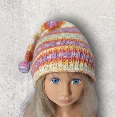 Gestrickte gestreifte Kindermütze in Pastellfarben mit Bommel auf dem Kopf einer Puppe.