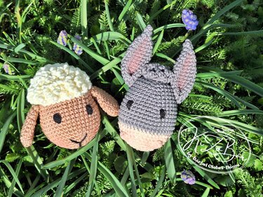 Gehäkeltes Schaf und Esel im grünen Gras mit lila Blüten