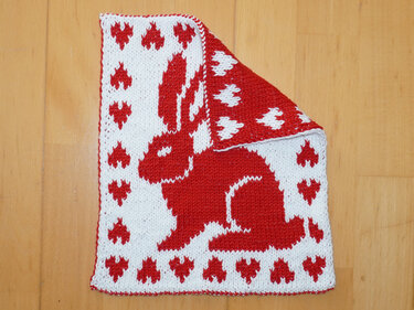 Gestrickter rot-weißer Topflappen mit Hasen- und Herzmuster, Ecke umgeschlagen