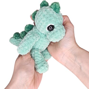 Mintgrüner gehäkelter Drache (Amigurumi) in Händen gehalten