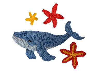 Handmade crocheted blue whale with a light blue belly, two red starfish, and one yellow starfish on a white background.
