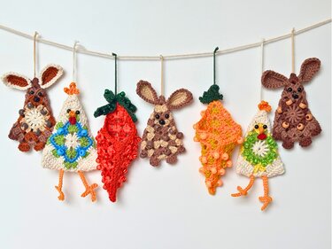 Seven beaded crochet Easter motifs on a twine garland: two bunnies, two chicks, two carrots and one strawberry, photographed on a white background.