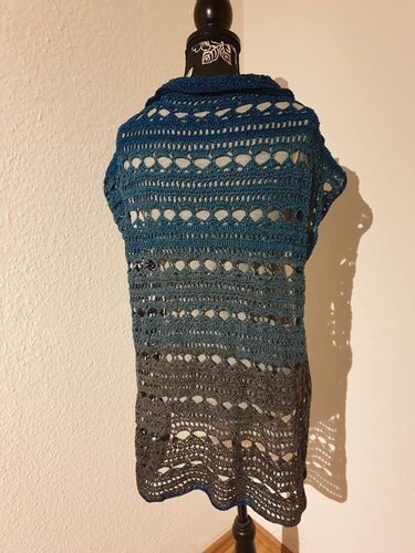 Rückenansicht eines gehäkelten Dreieckstuchs in Blau‑Grau mit Lochmuster auf einer Schaufensterpuppe