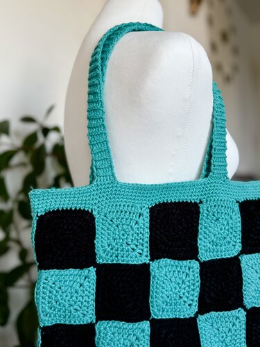 Teal and black crocheted checkerboard tote bag made from granny squares on a mannequin