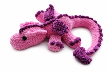 Rosa-lila gehäkelter Amigurumi-Drache auf weißem Hintergrund