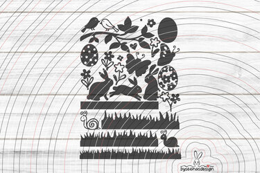 Schwarze Silhouetten mit separaten Elementen: Hasen, gestufte Grasstreifen, Ostereier, Blumen, Vögel, Schmetterlinge und Schnecken auf hellem Holz.