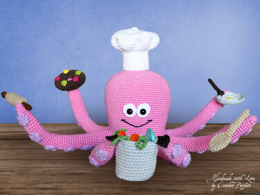 Rosa gehäkelter Oktopus-Amigurumi mit Kochmütze und gehäkelten Küchenutensilien