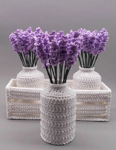 Three white crocheted vases in a tray with purple crocheted lavender-style stems