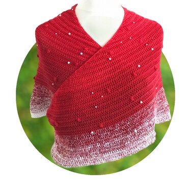 Rotes gehäkeltes Halbrundtuch mit weißen Perlen und Noppenmuster auf einer Schneiderpuppe vor grünem Hintergrund.