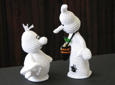 Zwei weiße gehäkelte Gespenster-Amigurumi auf dunklem Untergrund, eines mit Mini-Süßigkeitstasche und Spinnen-Applikation
