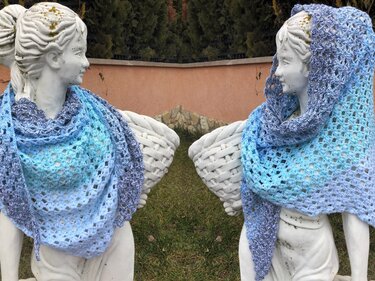 Gehäkeltes Dreieckstuch blau‑lila mit offenem Netzmuster und Muschelkante, drapiert auf weißer Skulptur