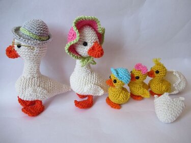 Gehäkelte Amigurumi: zwei weiße Gänse und drei kleine gelbe Küken, eines in einer Eierschale.