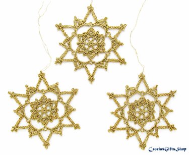 Three golden crocheted snowflake ornaments with hanging loops on a white background.