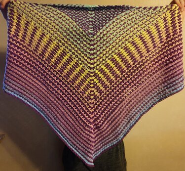 Gehäkeltes Dreieckstuch mit Farbverlauf, von zwei Händen gehalten, V‑förmige Mittelzunahme