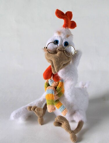 weißes gehäkeltes Huhn-Amigurumi mit runder Brille und gestreiftem Schal