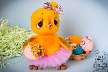 Kuscheliges gelbes Amigurumi-Küken mit Schleife und rosa Tüllrock neben bunten, gehäkelten Ostereiern im Korb