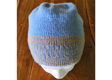 Hellblaue gestrickte Mütze mit beigem geometrischem Muster auf weißem Schaufensterkopf