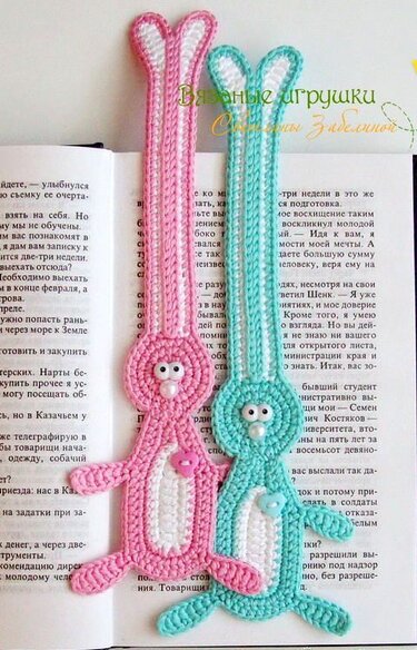 Zwei gehäkelte Hasen-Lesezeichen (rosa und türkis) in einem aufgeschlagenen Buch