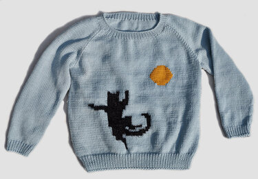 Strickmuster: hellblauer Kinderpullover mit schwarzer Katze und orangefarbener Sonne.