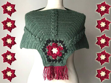 Salbeigrüner gehäkelter Poncho mit zentraler Blumenapplikation in Rot und Creme sowie roten Fransen
