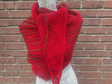 Rotes gestricktes Dreieckstuch mit Streifen und Ajourmuster auf Schneiderpuppe vor Backsteinwand