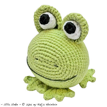 Light green crocheted amigurumi frog with large white eyes and a stitched smile.