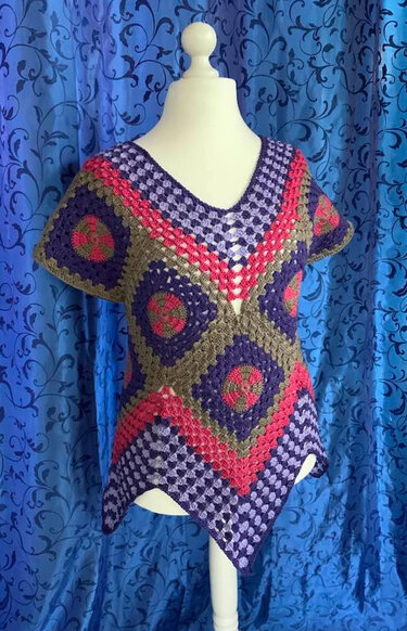 Gehäkelte Damen-Tunika aus bunten Granny-Squares mit V-Ausschnitt auf Schaufensterpuppe