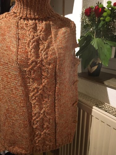 Orange-braun melierter Poncho mit hohem Rollkragen, zentralem Zopfmuster und seitlichen Holzknöpfen.