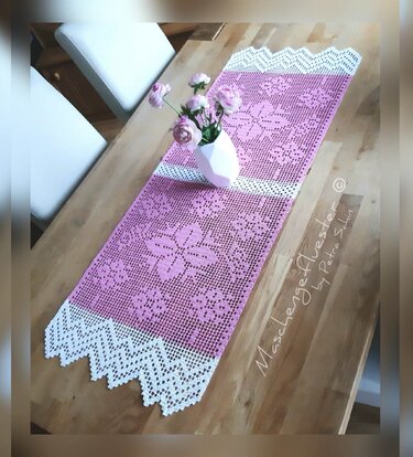 Rosa-weißer Filet-Häkel-Tischläufer mit Blumenmotiv und gezackter weißer Spitzenkante auf Holztisch, Vase mit Blumen