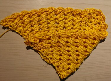 Nahaufnahme halbfertiges Dreieckstuch mit Stäbchen- und Luftmaschenreihen in Gelb