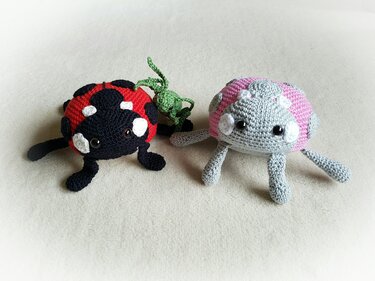 Drei gehäkelte Amigurumi-Insekten: roter Marienkäfer, kleine grüne Figur, grau-pinkes Fantasiewesen.