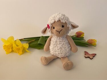 Gehäkeltes Amigurumi-Lamm mit Narzissen, Tulpen und Holzschmetterling