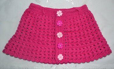 Gehäkelter Babyrock in Fuchsia mit Blumenknöpfen