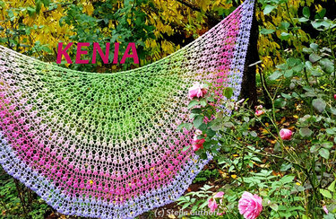Halbrundes gehäkeltes Tuch mit Farbverlauf in Grün, Pink und Lila, drapiert an Rosen im Garten