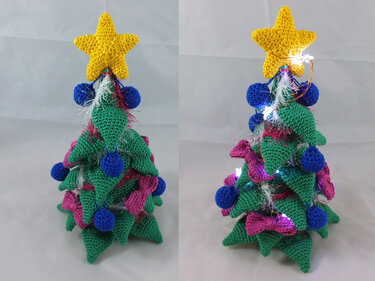 Gehäkelter Mini-Weihnachtsbaum mit gelbem Stern, blauen Kugeln, rosa Schleifen und Lichterkette