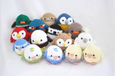 Mehrere kleine, gehäkelte Amigurumi‑Vögel in verschiedenen Farben und Mustern auf hellem Hintergrund.