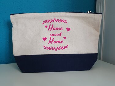 Nahaufnahme eines pinken Home sweet Home Plottdesigns auf beigefarbenem Stoff mit Ranken und Herzen