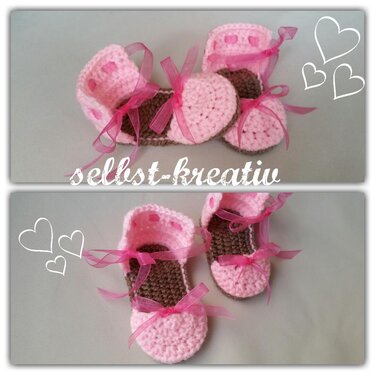 Zwei Paar rosa-braune gehäkelte Babyschuhe mit rosa Schleifen auf neutralem Hintergrund