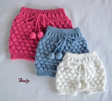 Drei gestrickte Baby-Windelhosen in Rosa, Hellblau und Weiß mit Noppenmuster, Rippenbund und Kordel mit Bommeln.