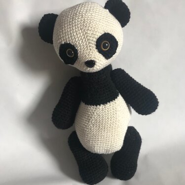 Crocheted black-and-white panda amigurumi sitting against a white background
