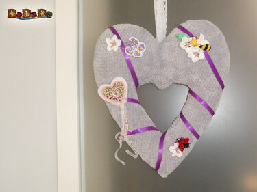 Gehäkelter grauer Herzkranz mit lila Bändern, Blumen, Schmetterling, Biene und Marienkäfer, hängend