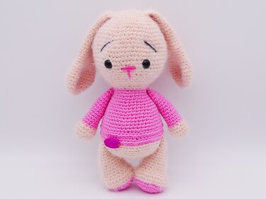 Kompakter gehäkelter Amigurumi-Hase mit langen Ohren, rosa Pullover und Knopfdetail