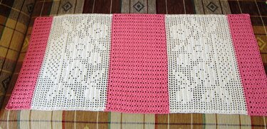 Gehäkelter Tischläufer in Rosa und Weiß mit durchbrochenem Blumenmuster auf kariertem Stoff